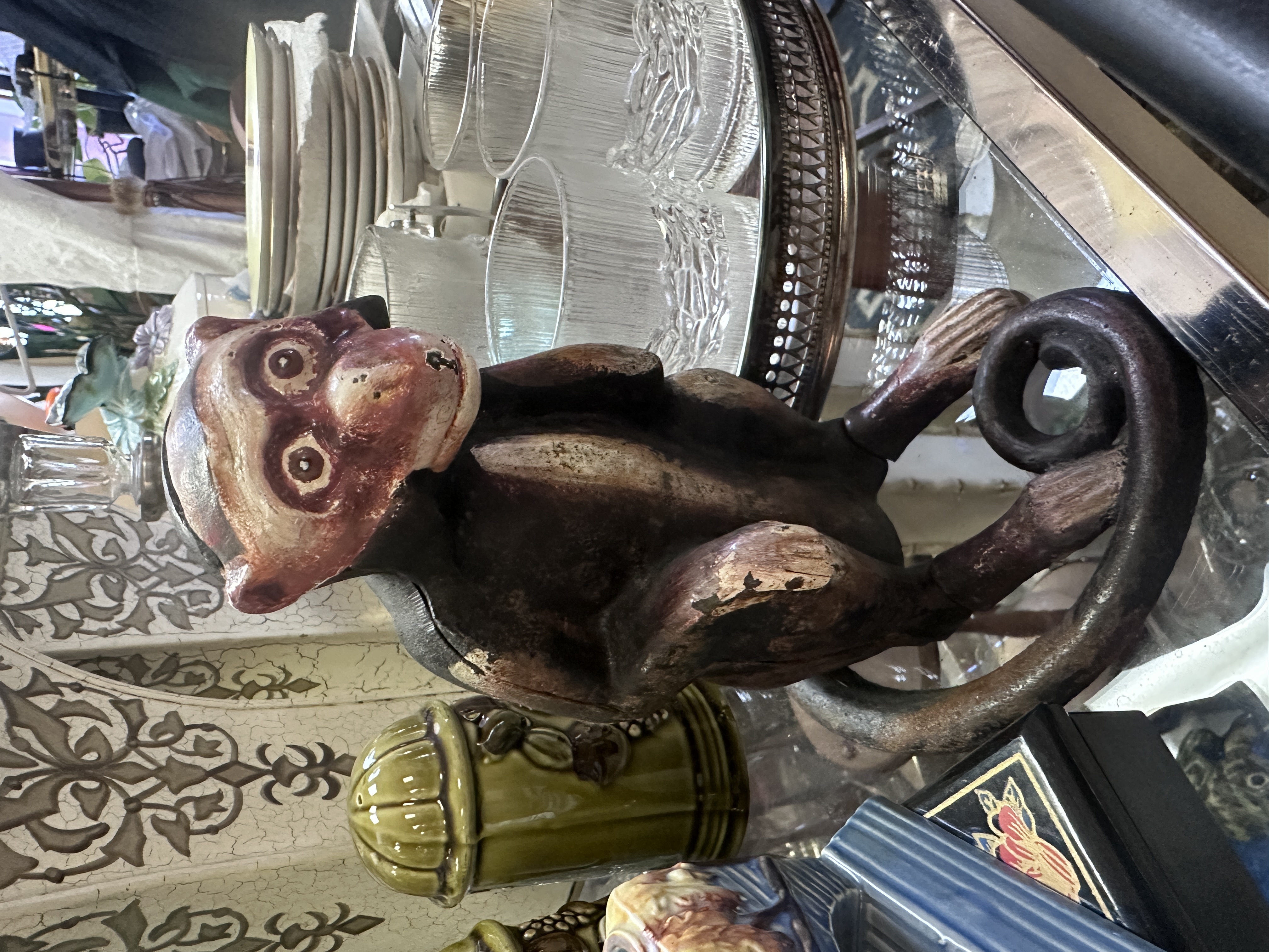Painted monkey figurine with curled tail on a glass display shelf